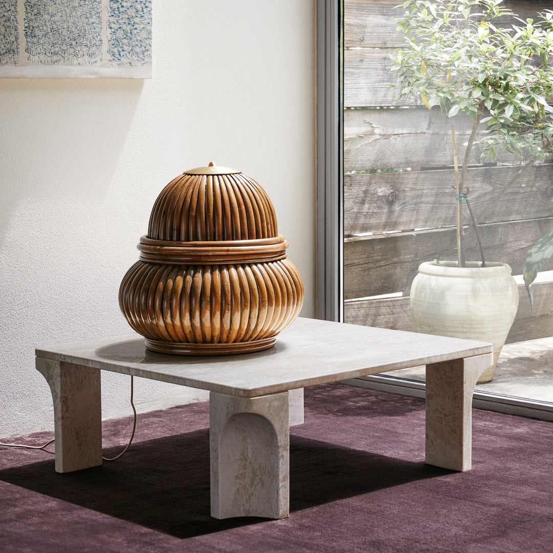 Wooden decorative item with a spiral pattern, sitting on a light-colored table against a dark purple rug.