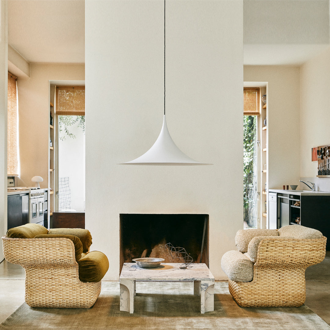 Natural rattan chairs in warm beige and olive green with a minimalist white pendant light in a cozy living room.