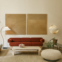 Rust-colored sofa against beige walls, with neutral-toned decor and a modern light fixture, creating a warm, inviting atmosphere.