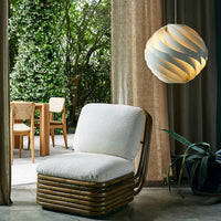"Modern cream cushion chair with natural wood accents, surrounded by greenery and soft, neutral-toned decor."