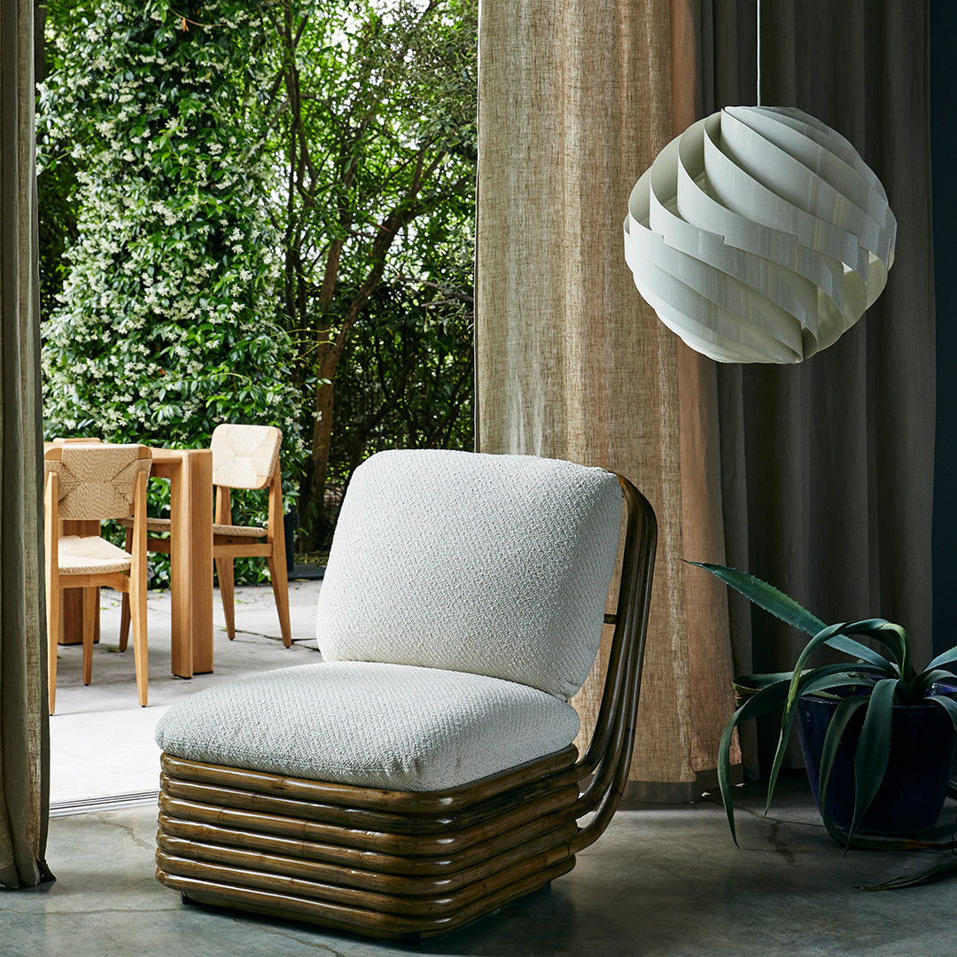 "Neutral beige seat cushion with striped wooden frame, set against lush greenery and soft, natural textiles."