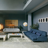 Modern living room featuring a dark blue sofa, light gray loveseat, and earth-tone decor against gray walls.