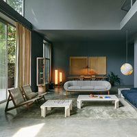 Modern living room with dark blue walls, neutral furniture, and natural wood accents. Soft lighting and textured textiles.