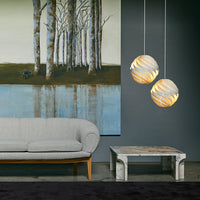 "Two decorative pendant lights with swirling cream and beige patterns above a gray sofa and abstract wall art."