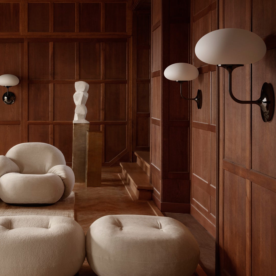 Cream-colored seating, warm wood paneling, and smooth, round lamp shades create a cozy, modern aesthetic.