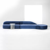 Curved modern couch in deep blue fabric with smooth lines and minimalist design, perfect for contemporary spaces.