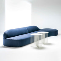 Elegant blue curved sofa with smooth fabric texture paired with two minimalist white side tables.
