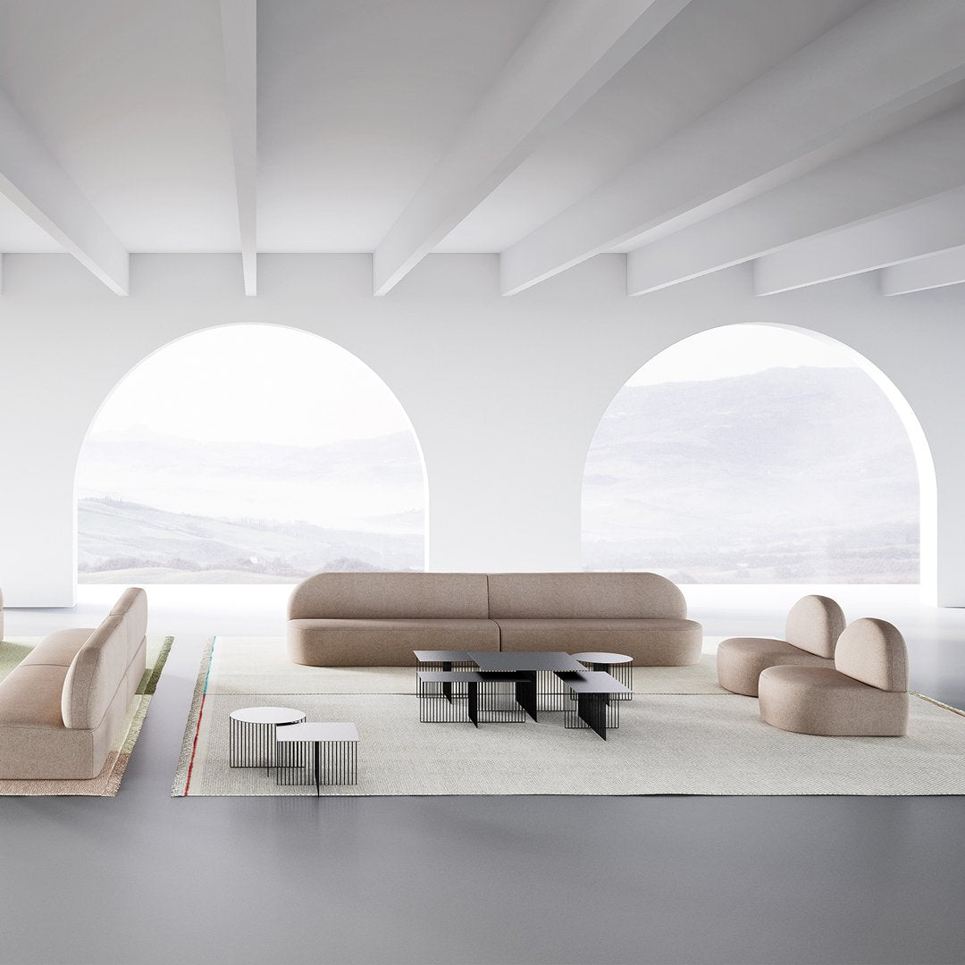 Beige curved sofa and chairs with sleek black and white tables, set against a minimalist white backdrop.