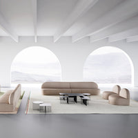 Beige curved sofa and chairs with sleek black and white tables, set against a minimalist white backdrop.