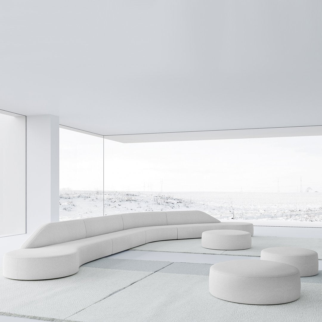 Modern white sectional sofa with smooth curves and rounded ottomans against a minimalist backdrop.