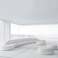 Modern white sectional sofa with smooth curves and rounded ottomans against a minimalist backdrop.
