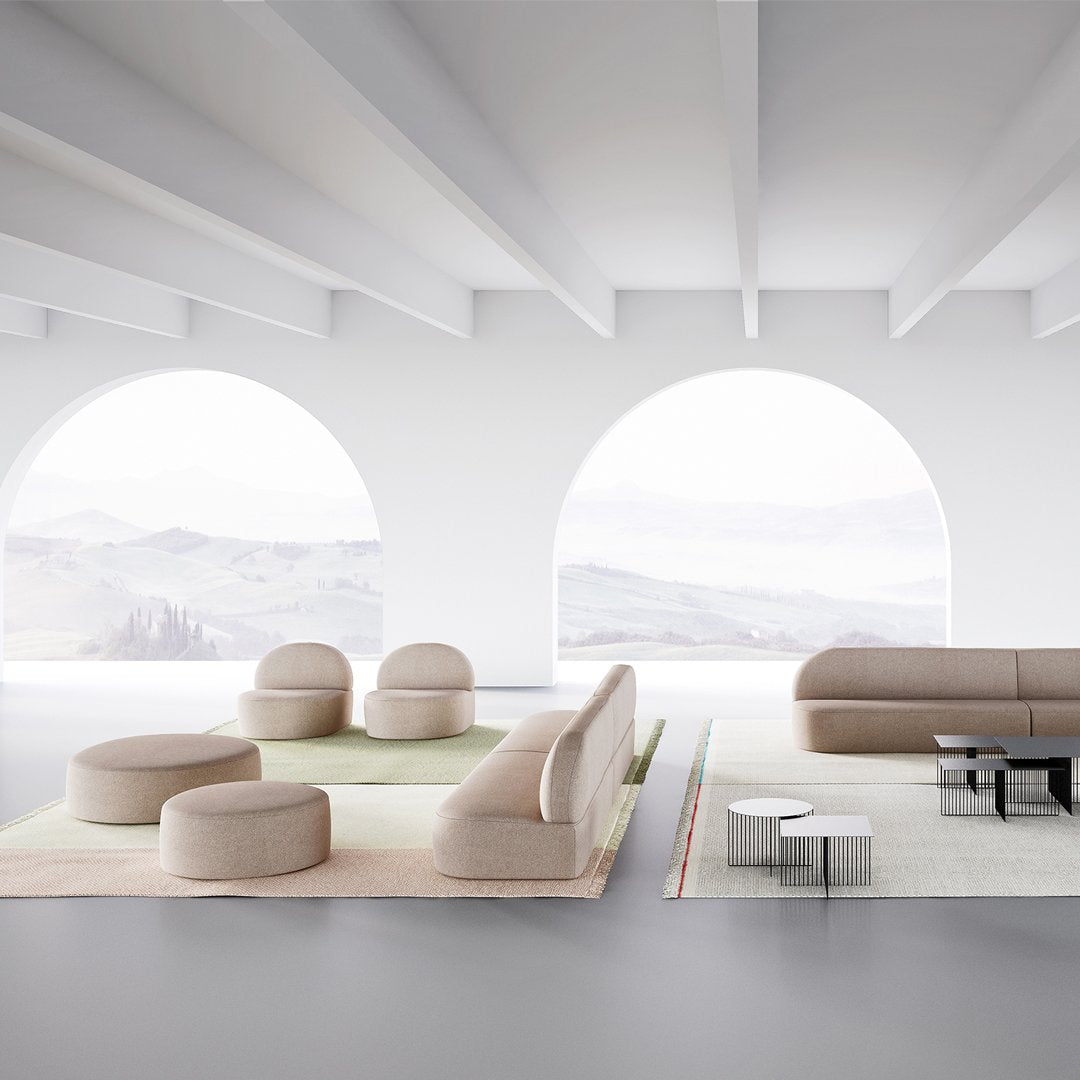 Light beige sofas and round seating on soft, neutral rugs against a minimalist setting with curved arch windows.