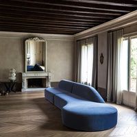 Curved blue sofa with a sleek, modern design, set against a neutral-toned, elegant interior.