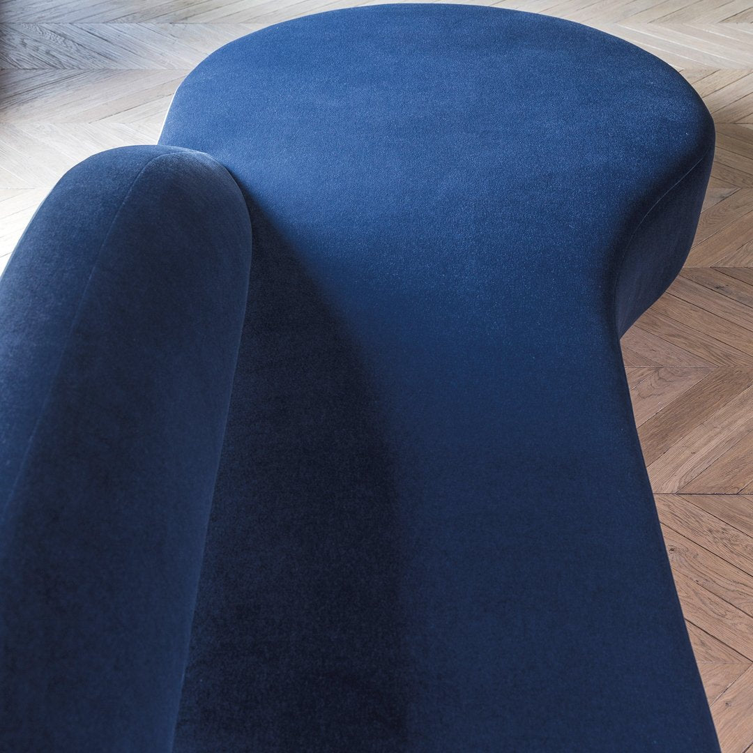 Curved navy blue velvet chaise lounge with a smooth, modern design and a soft texture. Perfect for stylish interiors.