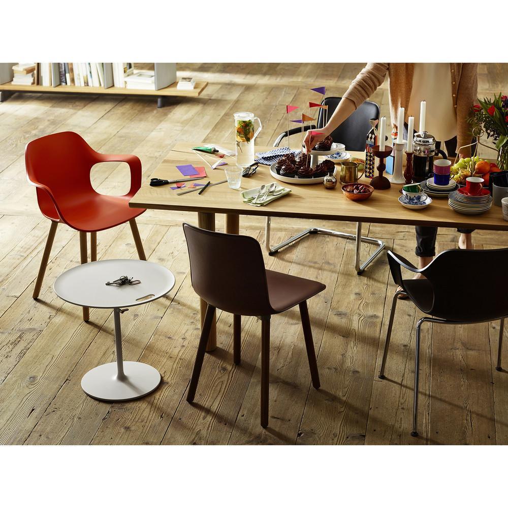 Colorful dining setup with a red armchair, brown and black chairs, and a white side table on a warm wooden floor.