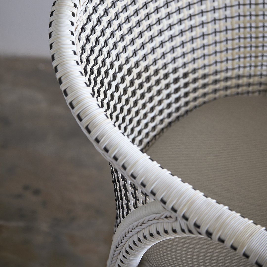White woven chair with contrasting black and white patterns, featuring a smooth, neutral seat. Perfect for modern decor.