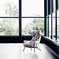 Colorful floral armchair with intricate patterns, featuring a vibrant mix of blues, reds, and greens in a modern setting.