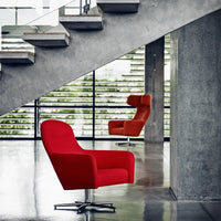 Red upholstered chairs with sleek designs, set against a modern concrete backdrop and large glass windows.