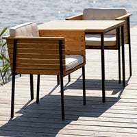 Modern wooden dining table set with light beige cushions and sleek black metal legs, perfect for outdoor settings.