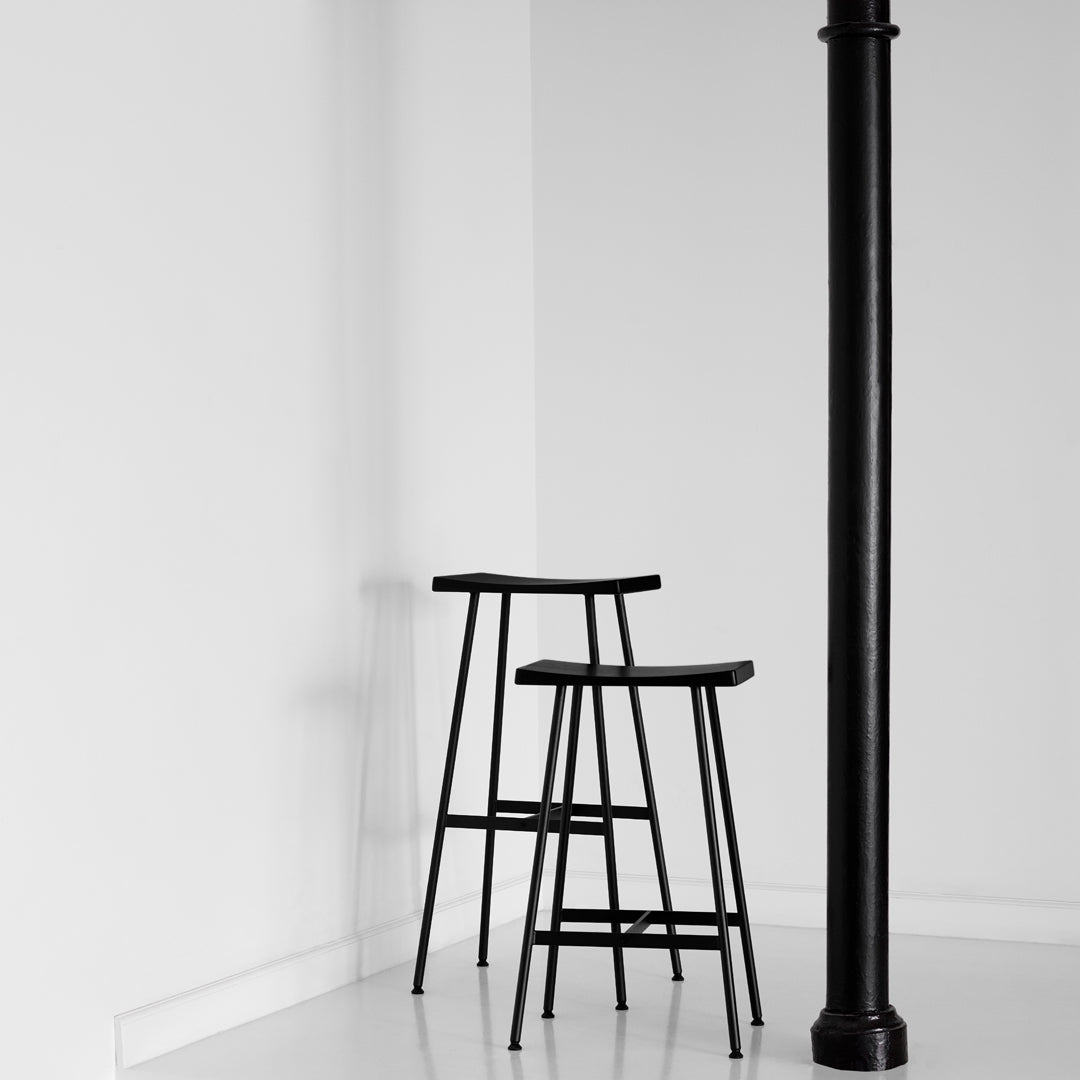Black wooden bar stools with a minimalistic design against a white background, showcasing modern simplicity.