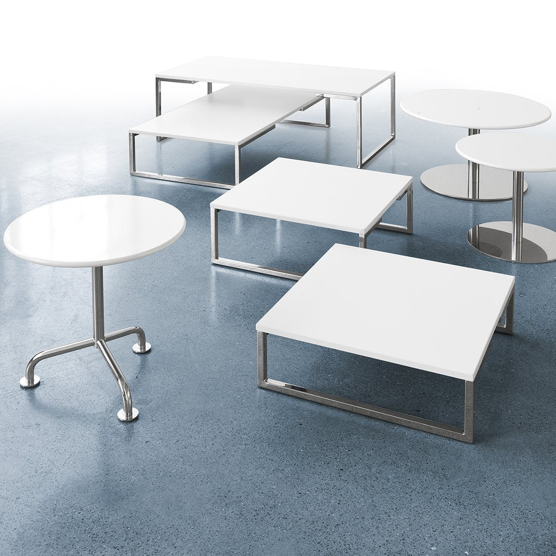 Modern white tables with sleek metal frames, featuring various geometric shapes and minimalist designs on a polished surface.