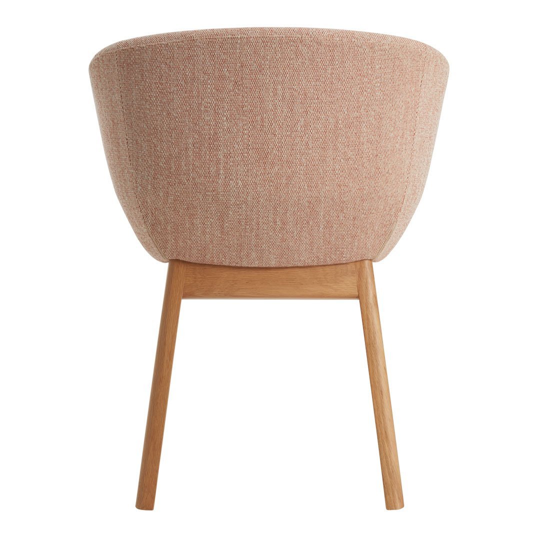 Pink textured fabric chair with wooden legs, showcasing a modern design and soft hues for a cozy ambiance.