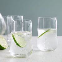 Clear glass tumblers with minimalist design, featuring bubbles and lime slices against a soft pastel background.