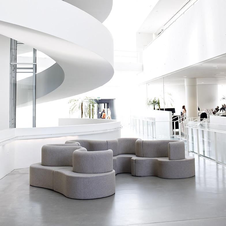 Light gray modular sofa with a smooth, rounded design, set against a bright, minimalist interior.