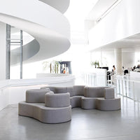 Light gray modular sofa with a smooth, rounded design, set against a bright, minimalist interior.