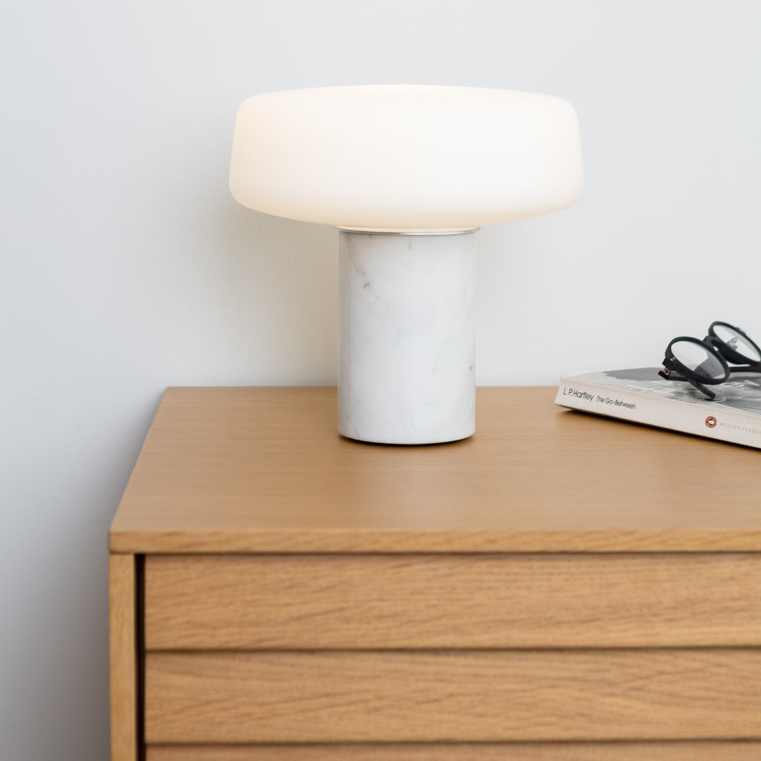 Modern white lamp with a smooth marble base, featuring a soft, round shade, complementing warm wood tones.