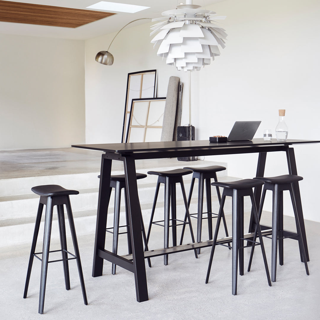 Sleek black bar table with matching stools, featuring minimalist design and a modern monochromatic color scheme.
