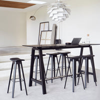 Sleek black bar table with matching stools, featuring minimalist design and a modern monochromatic color scheme.