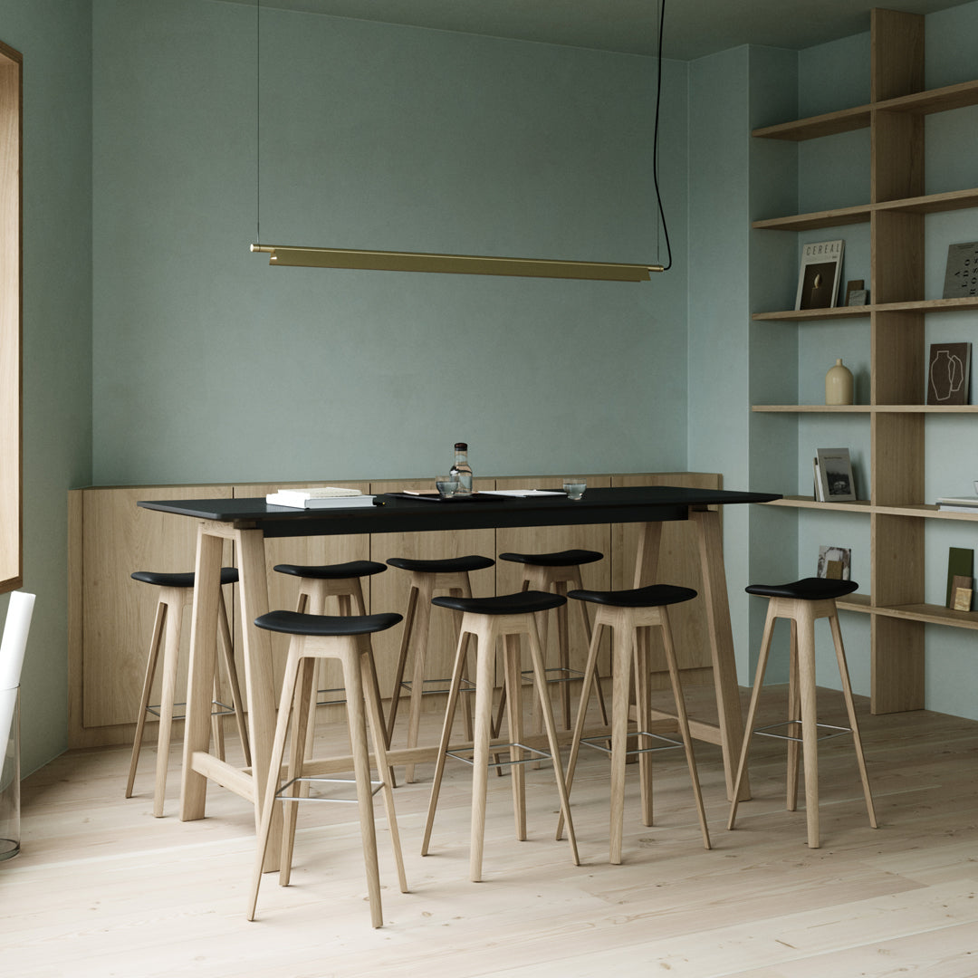 Minimalist bar area with soft blue walls, natural wood finishes, black seating, and clean lines in a modern design.