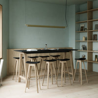 Minimalist bar area with soft blue walls, natural wood finishes, black seating, and clean lines in a modern design.