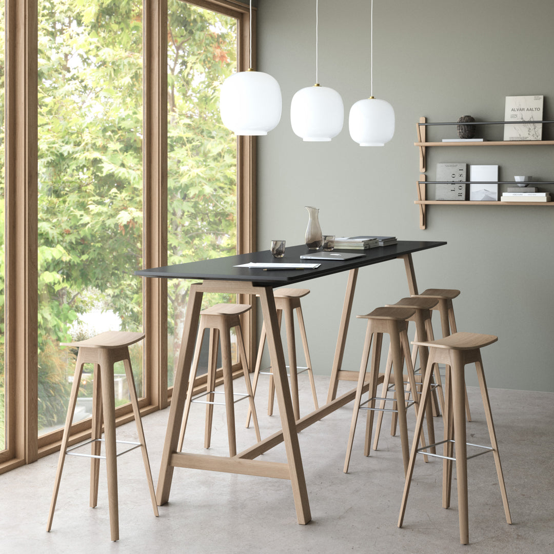 "Stylish black tabletop with natural wood stools, complemented by round white pendant lights and a soft green wall backdrop."