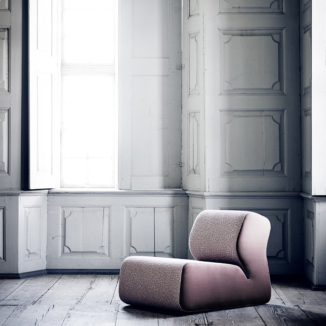 Modern two-tone chair in soft pink and neutral gray, featuring smooth curves set against a light, airy room.