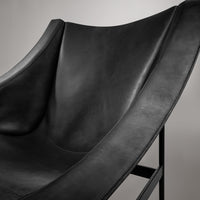 Black leather chair with a smooth, curved design and minimalistic metal frame. Elegant and modern accent piece.