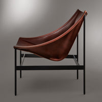 Brown leather lounge chair with a sleek black metal frame against a neutral background. Elegant, minimalist design.