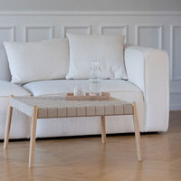 Light gray suede sofa with a woven beige coffee table, featuring a striped pattern and natural wood legs.