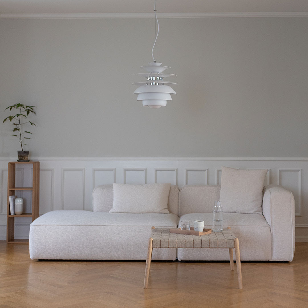 Modern white sofa with plush cushions, paired with light wood furniture and a soft grey wall, enhancing the minimalist design.