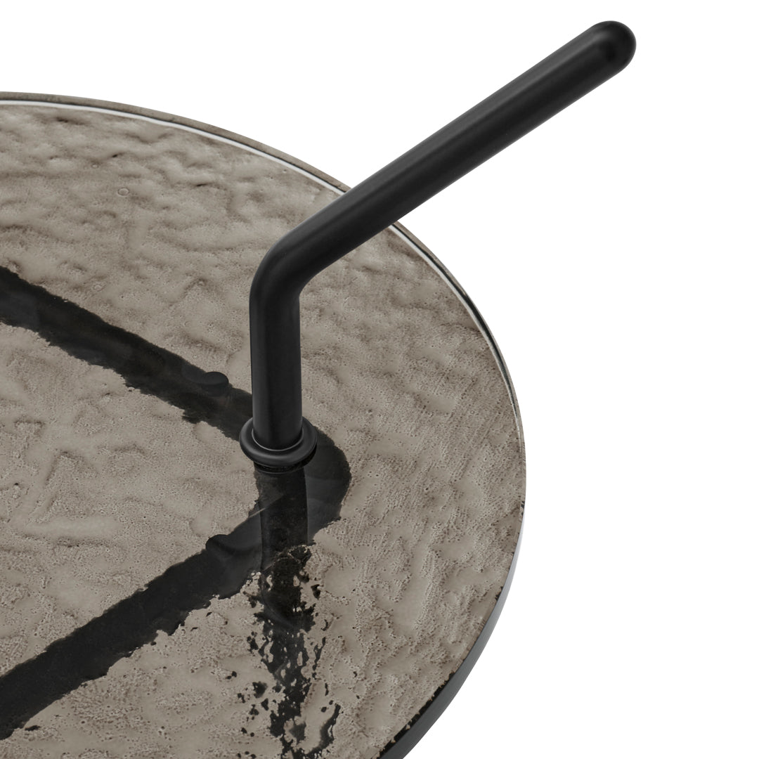 Black metal straw on a textured, gray glass surface with distinct patterned lines.