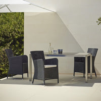 Outdoor dining set featuring black wicker chairs and a sleek gray table, set against a neutral backdrop.