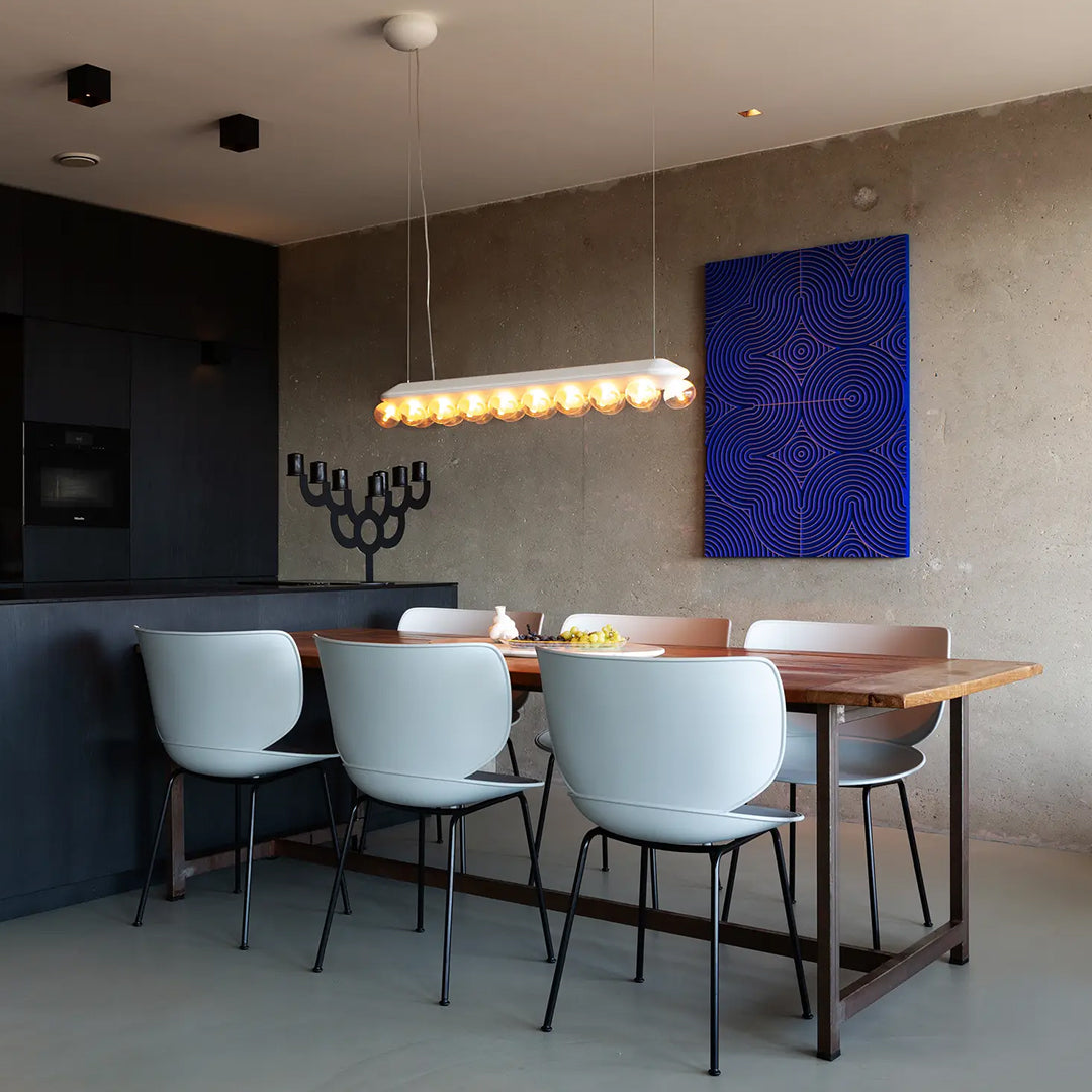 Modern dining room featuring white chairs, wooden table, and a blue geometric artwork on a gray wall.