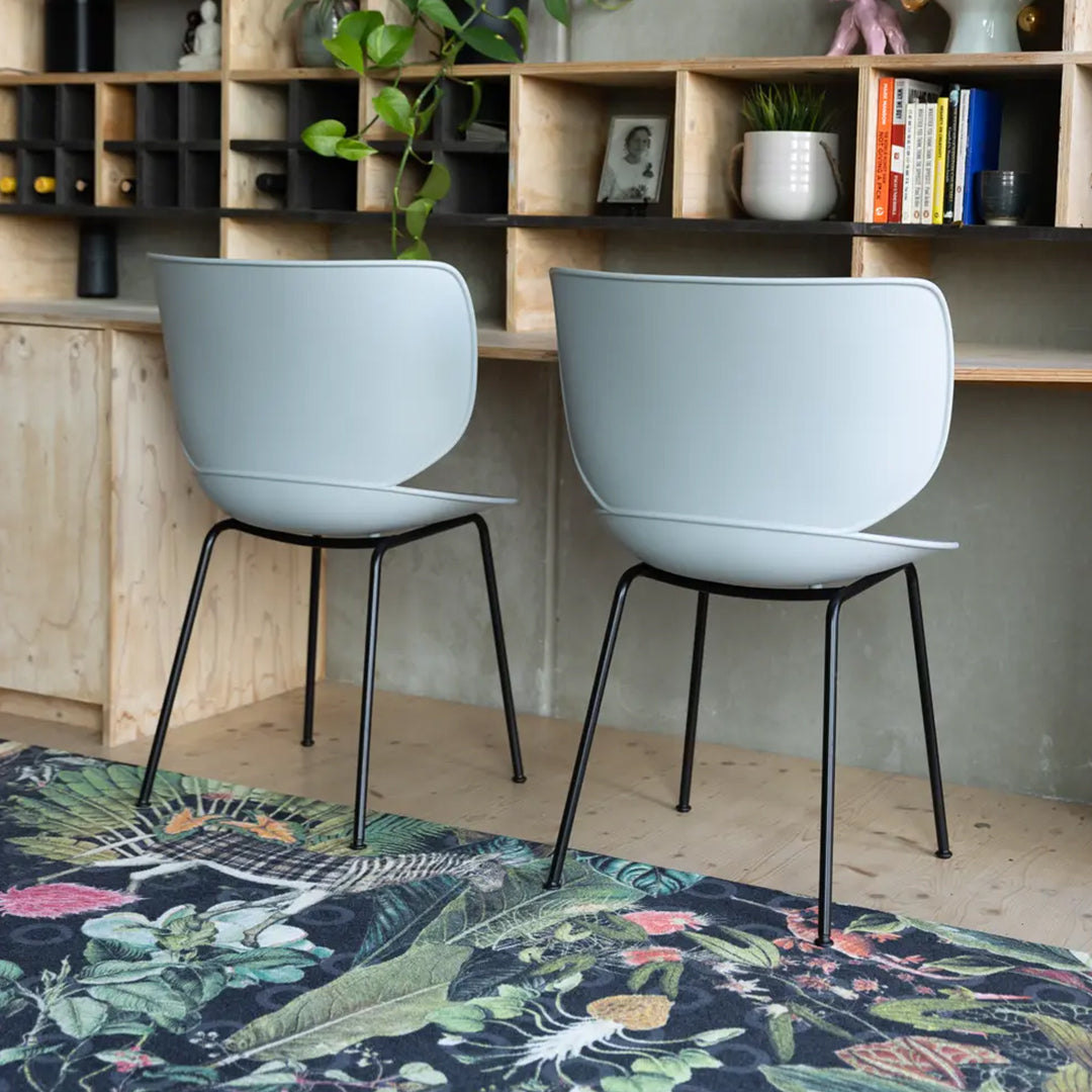 Gray chairs with sleek design on vibrant patterned rug featuring tropical leaves and colorful floral accents.