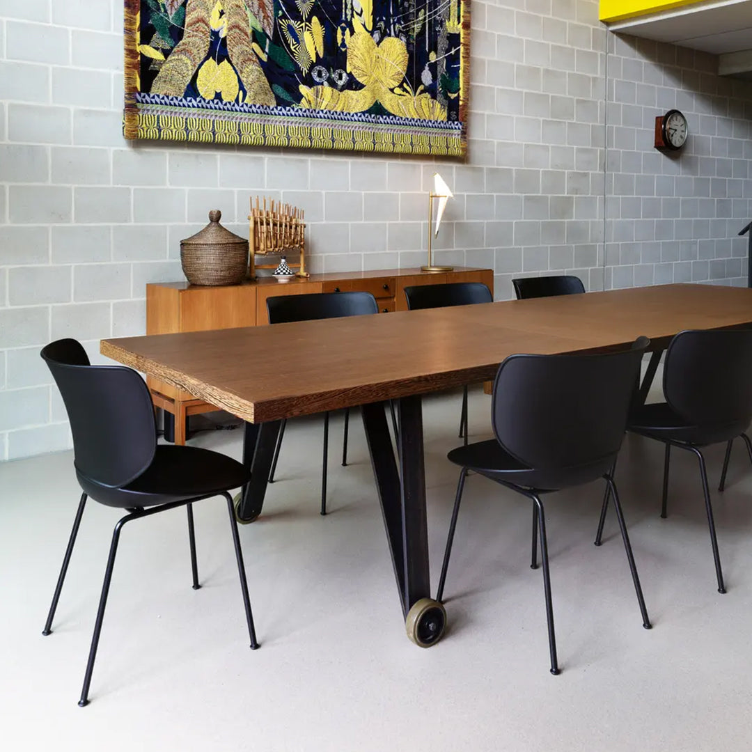 Modern wooden dining table with black chairs, featuring a minimalist design and neutral color palette.