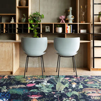 Light blue modern chairs on a vibrant, floral-patterned dark rug in a minimalist setting.