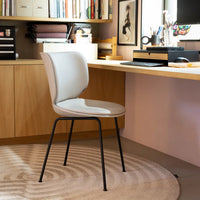 Light gray chair with smooth upholstery and black metal legs, set against a soft, circular patterned rug.