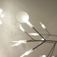 Modern light fixture with sleek black branches and spherical white bulbs, creating an elegant and minimalistic design.