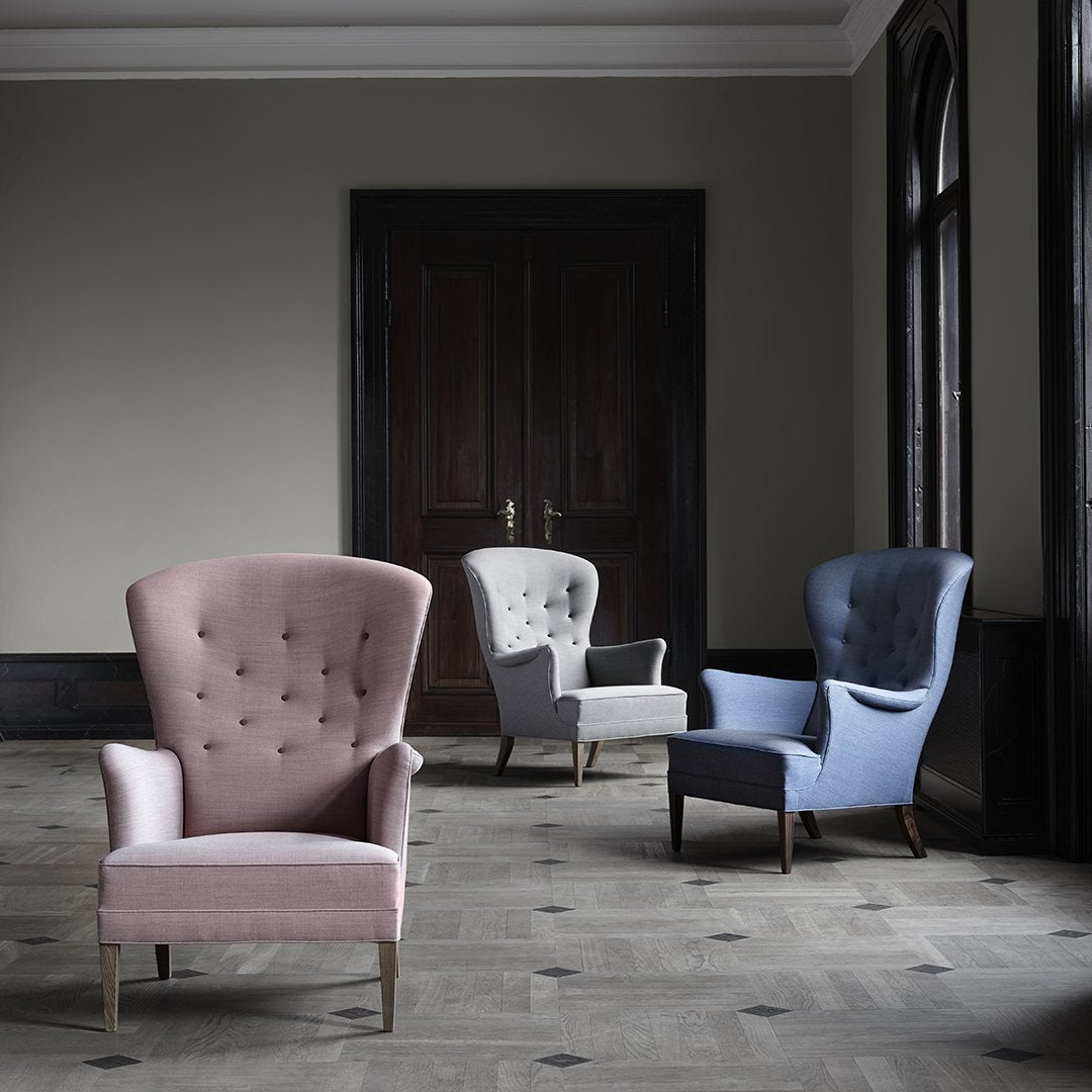 Elegant armchairs in soft pink, gray, and blue fabrics with tufted detailing on a neutral floor backdrop.