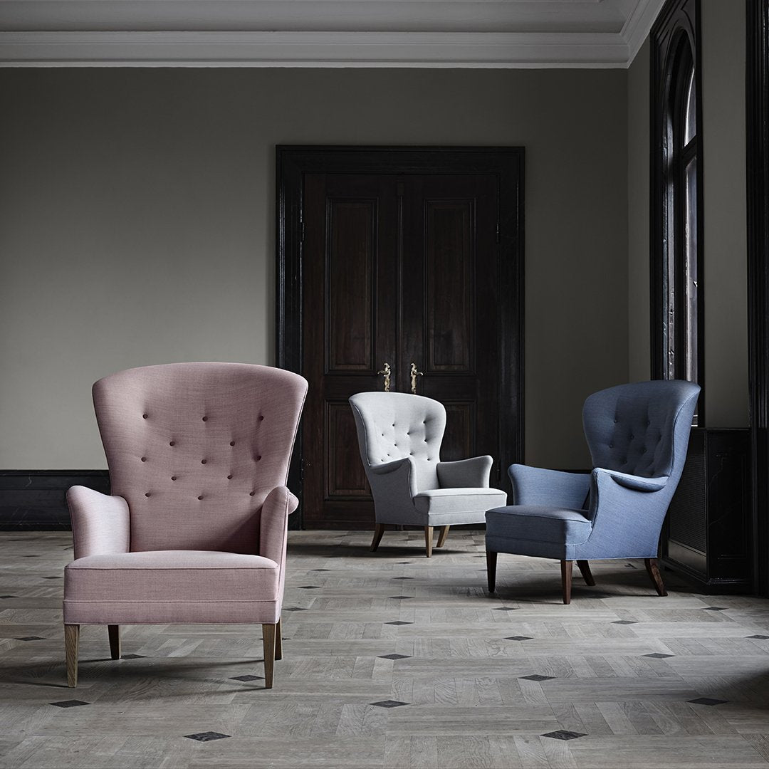 Stylish armchairs in pink, white, and blue upholstery featuring classic tufted designs in an elegant setting.